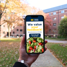 Photograph of a person's hand holding a cell phone with the MDining survey on the screen.