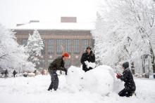 Photograph of students making a snowman.