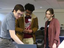 Photograph of three students looking at a laptop.