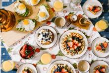 Photograph of a table with breakfast foods and drinks, including pancakes, waffles, orange juice, and coffee.