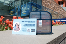 Photograph of a "Borrow at MDining" poster with a QR code to download the Fill it Forward app.