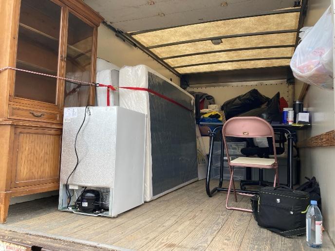 Photograph of the inside of a moving truck filled with furniture, appliances, and other items.