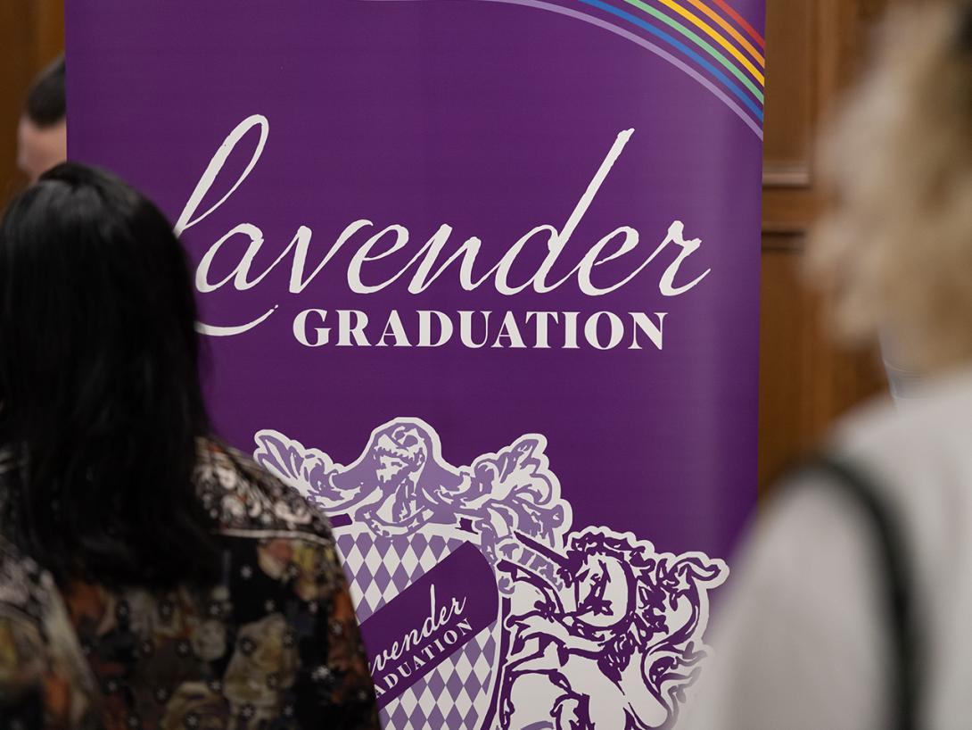 Photograph of students looking at a large poster for Lavender Graduation
