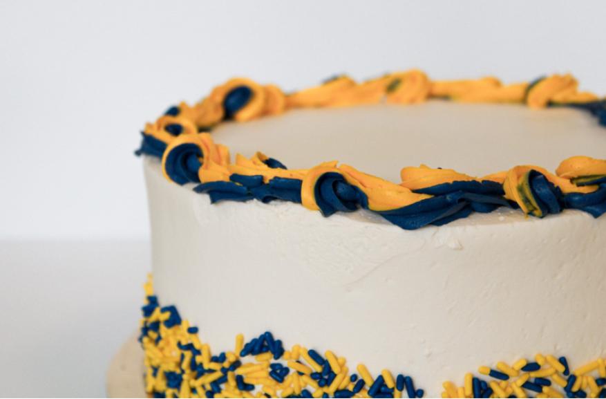 Photograph of a cake with maize and blue frosting.