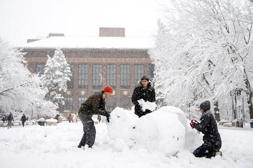 Photograph of students making a snowman.