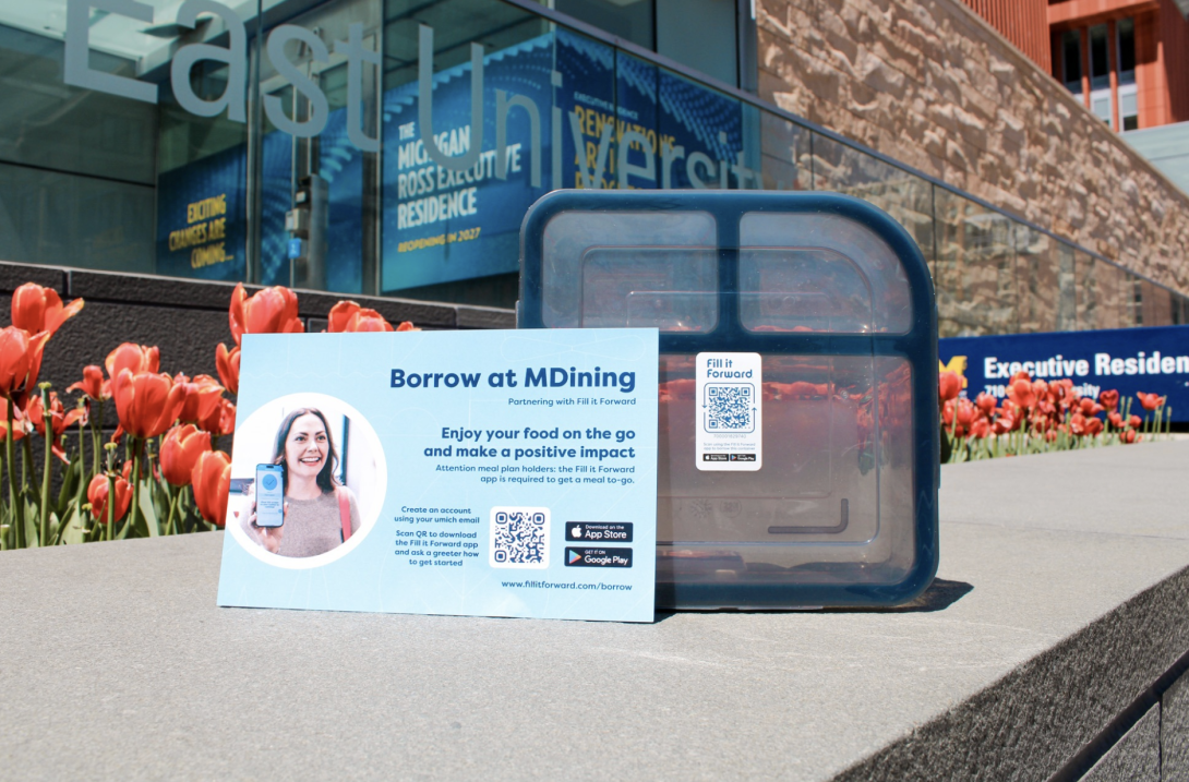 Photograph of a "Borrow at MDining" poster with a QR code to download the Fill it Forward app.